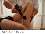 Relieving Leg Tension With a Percussion Gun in the Comfort of Home. Стоковое фото, фотограф Aleksandr Golubev / Фотобанк Лори