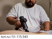 Giving Muscle Tension Relief With a Percussion Massager. Стоковое фото, фотограф Aleksandr Golubev / Фотобанк Лори