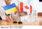 Unrecognizable girl sets midget flags of Canadа and Ukrainе before international negotiations. Стоковое фото, фотограф Яков Филимонов / Фотобанк Лори