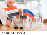 Unrecognizable girl sets midget flags of Russia and Iraq before international negotiations. Стоковое фото, фотограф Яков Филимонов / Фотобанк Лори