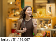 Beautiful young girl customer choosing something in souvenir shop during tourist trip in Spain. Стоковое фото, фотограф Яков Филимонов / Фотобанк Лори