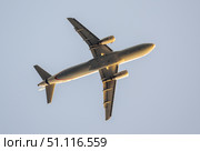 Low angle view of a passenger airplane flying high in a clear blue sky, showcasing the underside of the aircraft. Стоковое фото, фотограф Данил Руденко / Фотобанк Лори