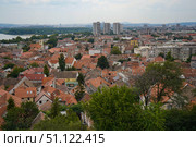 Wide panoramic view of Zemun with churches and red roofs along the Danube, Belgrade visible in the distance across the river. Стоковое фото, фотограф Ирина Старикова / Фотобанк Лори