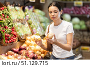 Girl client near vegetable stand in store choose onion. Стоковое фото, фотограф Яков Филимонов / Фотобанк Лори