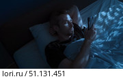 Young man uses his phone at night in bed, scrolling through his social media. Стоковое видео, видеограф Arsenii Palivoda / Фотобанк Лори