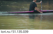A kayaker propels forward with skill, slicing through calm waters, creating splashes as the paddle cuts through the surface. A close-up of an athlete in a kayak. Preparation for competition. Стоковое видео, видеограф Воловодов Владимир / Фотобанк Лори