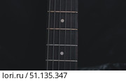 A close-up of the electric guitar's fingerboard shows off the polished deck, shiny metal fretboard and white fret markers on a dark textured background. Стоковое видео, видеограф Воловодов Владимир / Фотобанк Лори