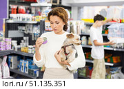 Buyers woman with Yorkshire Terrier choose healthy food and nutrition for pet in tin can. Стоковое фото, фотограф Яков Филимонов / Фотобанк Лори