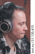 Close-up of a man wearing large headphones, a plaid shirt and a casual atmosphere. The guitarist is working on recording in the studio. Стоковое видео, видеограф Воловодов Владимир / Фотобанк Лори