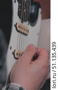Close-up of a guitarist's hand playing an electric guitar, plucking the strings with a plectrum near the pickups. The guitar has a black and white body. Стоковое видео, видеограф Воловодов Владимир / Фотобанк Лори