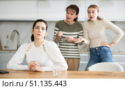Upset middle-aged woman sitting at the kitchen table with her back to women quarreling to her. Стоковое фото, фотограф Яков Филимонов / Фотобанк Лори