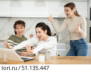 Three happy middle-aged woman expressing joy for winning in the kitchen. Стоковое фото, фотограф Яков Филимонов / Фотобанк Лори