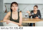 Upset middle-aged woman sitting at the kitchen table with her back to another lady quarreling to her. Стоковое фото, фотограф Яков Филимонов / Фотобанк Лори