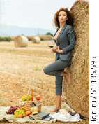 Woman in business suit standing with glass of wine near hay bale. Стоковое фото, фотограф Яков Филимонов / Фотобанк Лори
