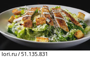 Rotating caesar salad featuring crispy croutons, shaved parmesan, breaded chicken slices on pristine white plate against dark backdrop. Стоковое AI-видео, аниматор Юрий Поздников / Фотобанк Лори