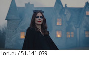 A cloaked figure stands confidently by a spooky old mansion as fog rolls in at dusk. Стоковое AI-видео, аниматор Данила Большаков / Фотобанк Лори
