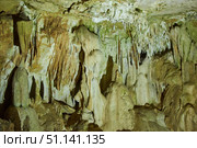 Dark cave view from inside with a lumen. Stalactites and stalagmites inside the stone grotto. Colorful stones in the cave. Lighting electricity beauty of the cave. (2019 год). Стоковое фото, фотограф Наталия Кирсанова / Фотобанк Лори