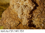 Dark cave view from inside with a lumen. Stalactites and stalagmites inside the stone grotto. Colorful stones in the cave. Lighting electricity beauty of the cave. (2019 год). Стоковое фото, фотограф Наталия Кирсанова / Фотобанк Лори
