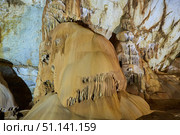 Dark cave view from inside with a lumen. Stalactites and stalagmites inside the stone grotto. Colorful stones in the cave. Lighting electricity beauty of the cave. (2019 год). Стоковое фото, фотограф Наталия Кирсанова / Фотобанк Лори