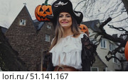 A woman dressed as a pirate poses next to glowing pumpkins in a historic setting during Halloween festivities. Стоковое AI-видео, аниматор Данила Большаков / Фотобанк Лори