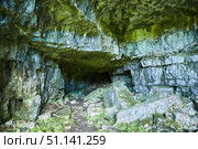 Dark cave view from inside with a lumen. Stalactites and stalagmites inside the stone grotto. Colorful stones in the cave. Lighting electricity beauty of the cave. (2019 год). Стоковое фото, фотограф Наталия Кирсанова / Фотобанк Лори