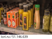 Supermarket shelves displaying a range of sauces and dressings. Bottles of Felix Special mango chilli sauce are clearly visible in the foreground, alongside packages of Tabasco hot sauce, a bottle of Heinz Worcestershire sauce, and other Felix salad dressings. The image conveys the atmosphere of a grocery store and the variety of flavours used to prepare and garnish dishes. The image can be used to illustrate themes related to cooking, shopping, food, gastronomy and retail. (2015 год). Редакционное фото, фотограф Анна Кривицкая / Фотобанк Лори