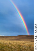 The shore of Lake Baikal after the rain. A bright colorful rainbow on the blue cloudy sky above the steppe meadows of Olkhon Island. Picturesque landscape. Weather phenomena and weather forecasts. Стоковое фото, фотограф Виктория Катьянова / Фотобанк Лори