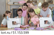 Woman teacher sews product surrounded by students. Стоковое видео, видеограф Яков Филимонов / Фотобанк Лори