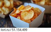 Crunchy Potato Chips Served in a White Box on a Rustic Wooden Table During a Snack Time Gathering. Стоковое AI-изображение, AI-художник Юлия Гапеенко / Фотобанк Лори