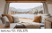 Cozy camper van interior with pillows and blanket, overlooking a serene lake and autumn mountains, perfect for travel and vanlife lifestyle themes. Стоковое AI-изображение, AI-художник Катерина Бондарец / Фотобанк Лори