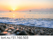 Serene beach scene at sunrise Gentle waves lapping against pebbled shore and colorful sky Soft focus. Стоковое фото, фотограф Наталья Семкина / Фотобанк Лори