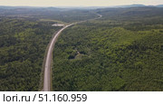 Stunning aerial view of a winding road through lush forest landscape in summer. Стоковое видео, видеограф Гурьянов Андрей / Фотобанк Лори