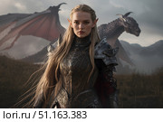 A female elf warrior with a dragon and a battlefield in the background. Стоковое AI-изображение, AI-художник Александр Поташев / Фотобанк Лори