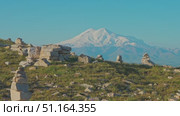 4k, panoramic view of the Bolshoy Bermamyt plateau with stone turrets built on a grassy slope, with the snow-capped peaks of Mount Elbrus in the background, at early morning, Stavropol Krai, Russia. Стоковое видео, видеограф Сергей Богомяко / Фотобанк Лори