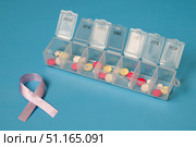 Daily pill organizer filled with pills and lavender awareness ribbon symbolizing general cancer awareness. Стоковое фото, фотограф Дмитрий Цветков / Фотобанк Лори