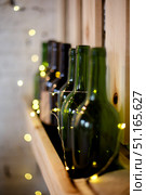 Yellow Christmas garland and green wine bottles on a wooden shelf. Стоковое фото, фотограф Aleksandra Selivanova / Фотобанк Лори