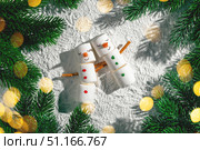 Two adorable marshmallow snowmen are embracing on a snowy background surrounded by christmas tree branches and warm, inviting lights, creating a festive and heartwarming scene. Стоковое фото, фотограф Ольга Ильина / Фотобанк Лори