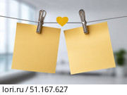 Yellow sticky notes clipped to clothesline, heart shaped paper between them, symbolizing romantic communication or heartfelt message. Стоковое AI-изображение, AI-художник Юрий Поздников / Фотобанк Лори