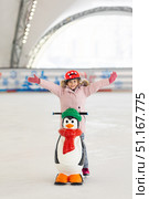 Happy little girl in warm pink coat and red safety helmet holding support and learning to skate on ice skating rink. Fall down and have fun. Winter sport, outdoors. Holiday and seasonal concept. Стоковое фото, фотограф Ирина Михайличенко / Фотобанк Лори