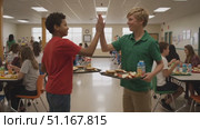 Students sharing lunch trays, high fiving while crowded school cafeteria buzzes with midday energy and socializing classmates. Стоковое AI-видео, аниматор Юрий Поздников / Фотобанк Лори