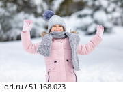Little girl having fun playing with fresh snow during snowfall. Snowball fight. Kid dressed in warm clothes, hat, hand gloves and scarf. Active outdoors leisure for child on nature in snowy winter day. Стоковое фото, фотограф Ирина Михайличенко / Фотобанк Лори