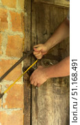 Man cutting padlock with hacksaw. Vintage wooden door in brick wall. Vertical video. Стоковое видео, видеограф Vadzim Yakubovich / Фотобанк Лори