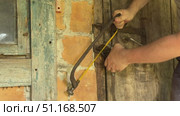 Man cutting padlock with hacksaw. Vintage wooden door in brick wall. Стоковое видео, видеограф Vadzim Yakubovich / Фотобанк Лори