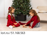 Little children girls play tic tac toe board game at home on the Christmas tree background. Children early development. Christmas and New Year holidays time. Board game and kids leisure concept. Стоковое фото, фотограф Ирина Михайличенко / Фотобанк Лори