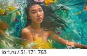An artistic portrayal showing the impact of plastic pollution in the ocean with a model immersed among colorful waste. Стоковое AI-видео, аниматор Данила Большаков / Фотобанк Лори