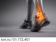 Leg with ankle joint pain icon. Foot wearing running shoes showing the bones in the ankle area. Grey floor. Feet with red effect of painful injury problems. Legs with anatomical detail glowing orange. Стоковое AI-изображение, AI-художник Марина Демидюк / Фотобанк Лори