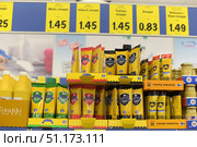 A photograph of a supermarket shelf with a selection of mustard in tubes and bottles. In the foreground are mustard pastes of the Herttua brand in multi-colored tubes: green - mild mustard, red - hot, black - strong. Nearby are tubes and packages of the Turun Sinappi brand. At the bottom, yellow plastic bottles with large volumes of mustard are visible. Above the shelf hang bright yellow price tags with inscriptions in Finnish and an indication of the cost. The image shows the display of goods in a European supermarket, the design of the shelves and the selection of seasonings for customers. (2015 год). Редакционное фото, фотограф Анна Кривицкая / Фотобанк Лори
