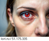 A woman with an intensely red eye gazes directly into the camera, her expression enigmatic. The backdrop adds a mysterious depth, enhancing the surreal atmosphere. Стоковое AI-изображение, AI-художник Ольга Игнашина / Фотобанк Лори