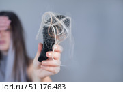 Hairbrush full of strands in young womans hands showing hair breakage and hair loss problem. Стоковое фото, фотограф Svetlana Golovco / Фотобанк Лори