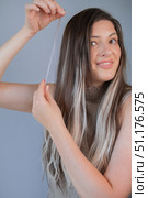 Woman holding hair strand with capsule demonstrating professional hair extension technique in beauty salon. Стоковое фото, фотограф Svetlana Golovco / Фотобанк Лори